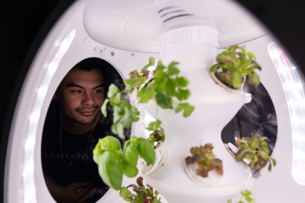 salon-habitation-photos-JulianHaber-4 man looking at seedlings growing in space age seedling sprouter