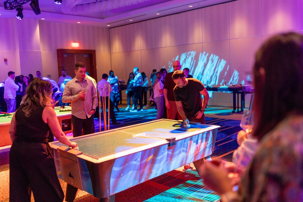 Brother24-NatCon - Credit Julian Haber-20240508-AA8A6821 People playing air hockey, photographed by event photographer Julian Haber using event ambient lighting.