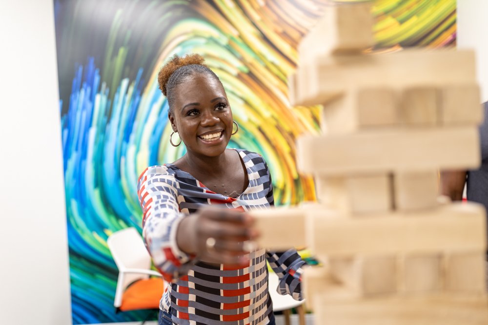 20220912-602A7866 Diversity in action: Black woman removing a block from a Jenga tower by Julian Haber