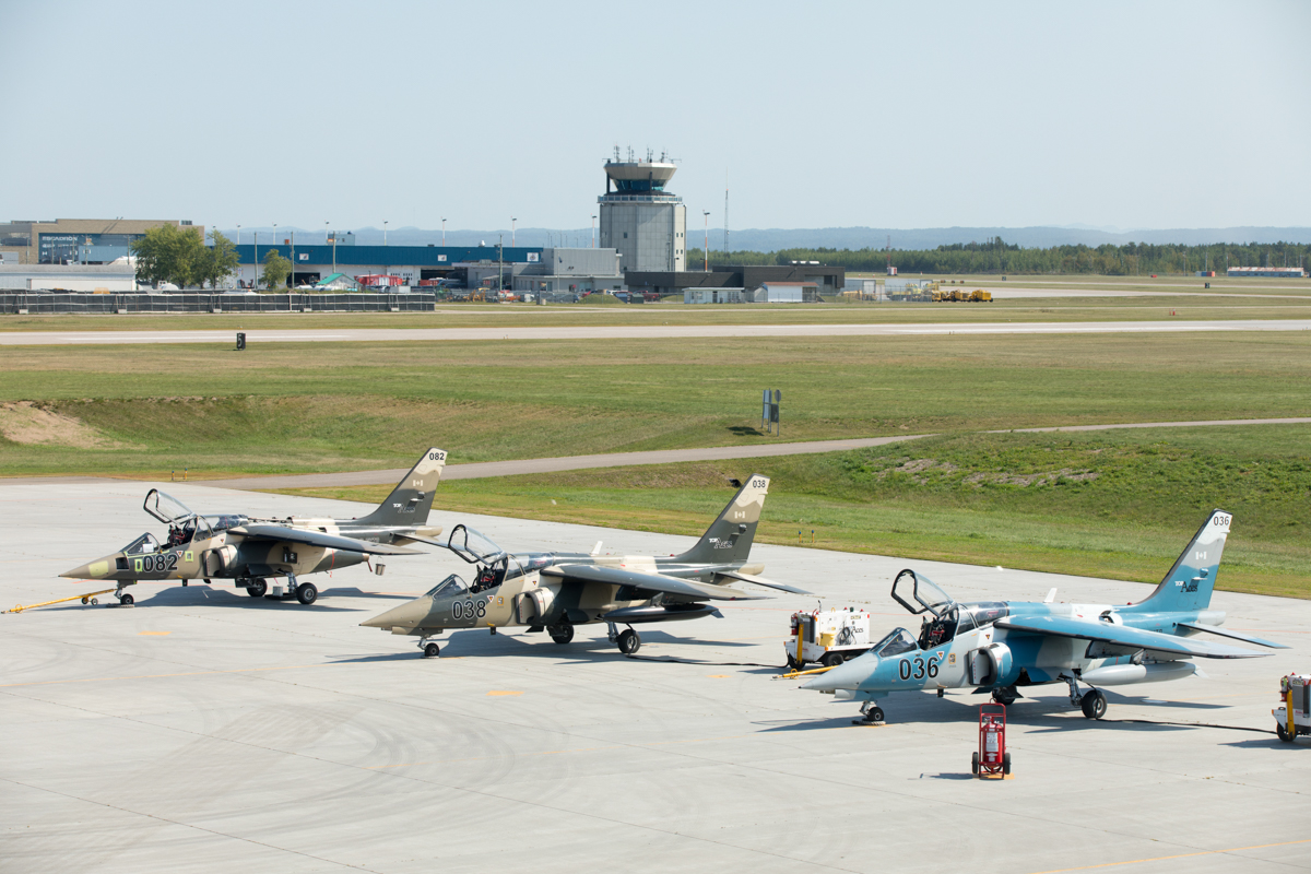 julian-haber-photography-employer-branding-montreal-22 Wide-angle landscape photography of aircraft on a Montreal airport tarmac with an air traffic control tower in the distance by Julian Haber