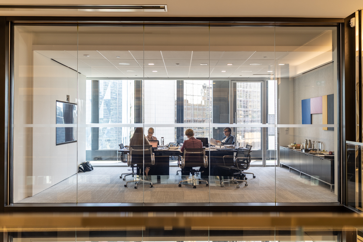 julian-haber-photography-employer-branding-montreal-39 Wide interior shot of a team of corporate professionals meeting around a table in a bright glass-walled boardroom by Julian Haber